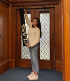 Person holding a 'Class of 2023' banner in a room with wooden walls and stained glass windows.