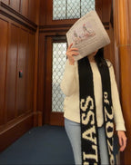 Person holding a book in front of their face in a wooden elevator with stained glass windows.